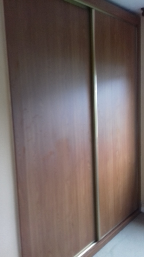 Armario empotrado con puertas en melamina castaño oscuro y tiradores en dorado .