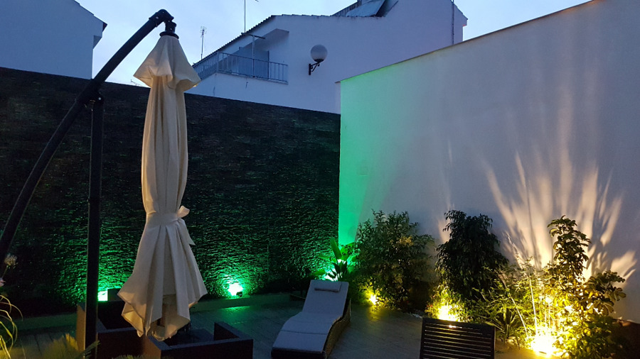 Patio con muro llorón iluminado con mobiliario de jardín