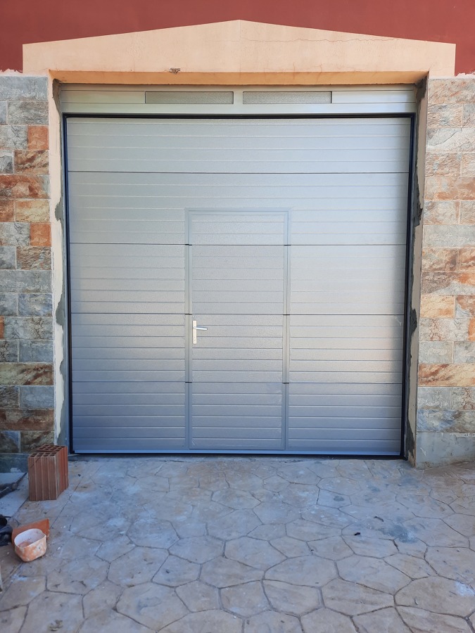 Puerta seccional con Puerta peatonal en gris plata