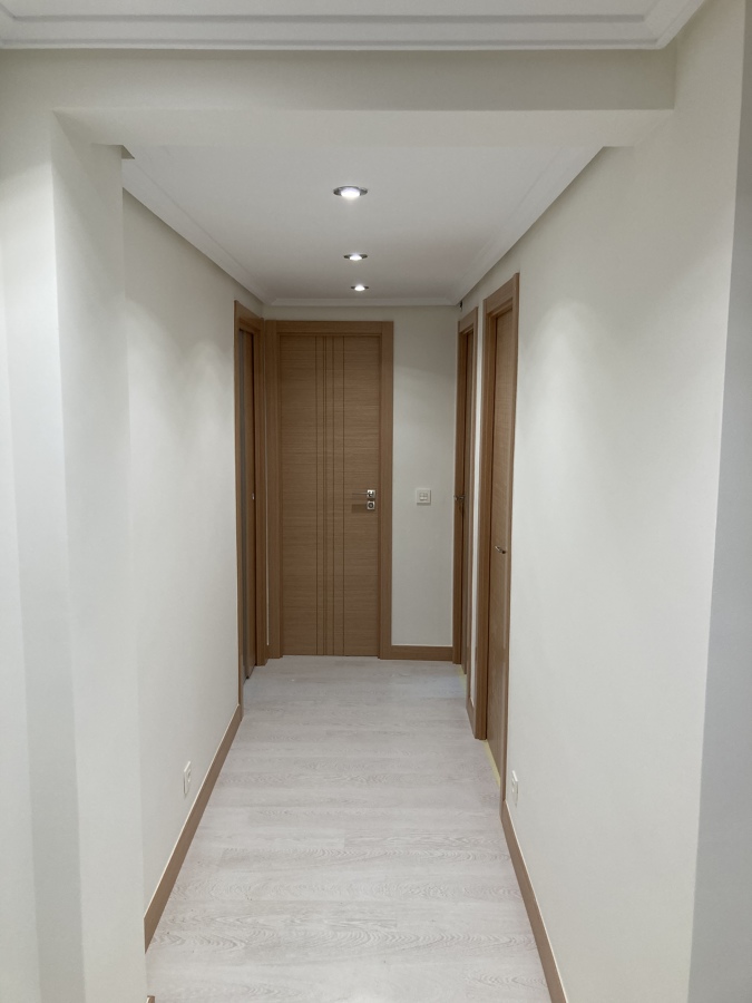 Suelo laminado en gris claro y puertas en color roble.