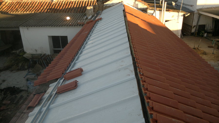 Colocacion de panel sandwich sobre cubierta antigua de madera y despues colocacion de teja ceramica roja sobre el panel.