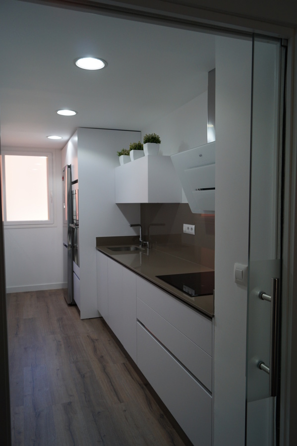 Cocina blanca suelo tarima y puerta de cristal