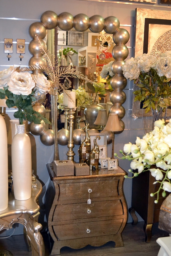 Espejo y mueble auxiliar en tonos dorados.