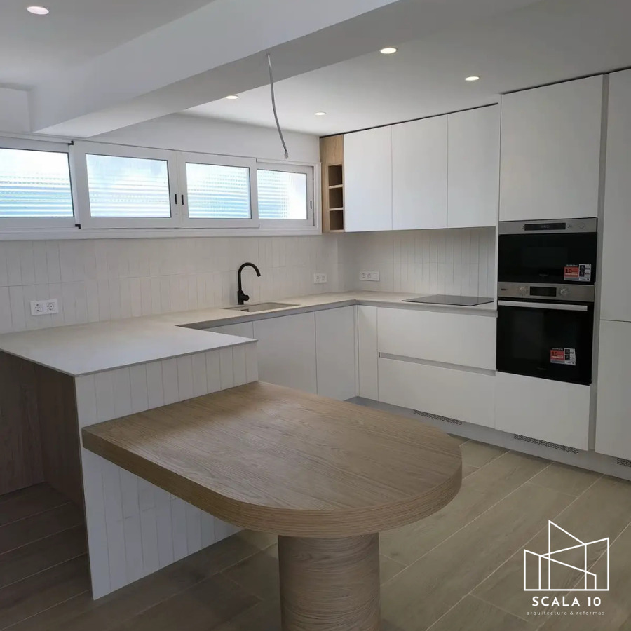 Cocina moderna integrada con mesón de madera y iluminación funcional