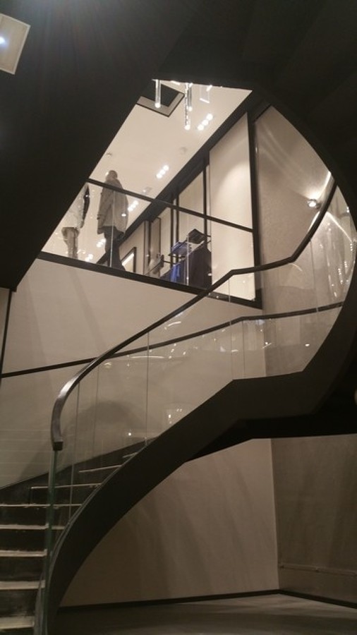 Detalle de escalera metálica helicoidal con barandilla de cristal curvo