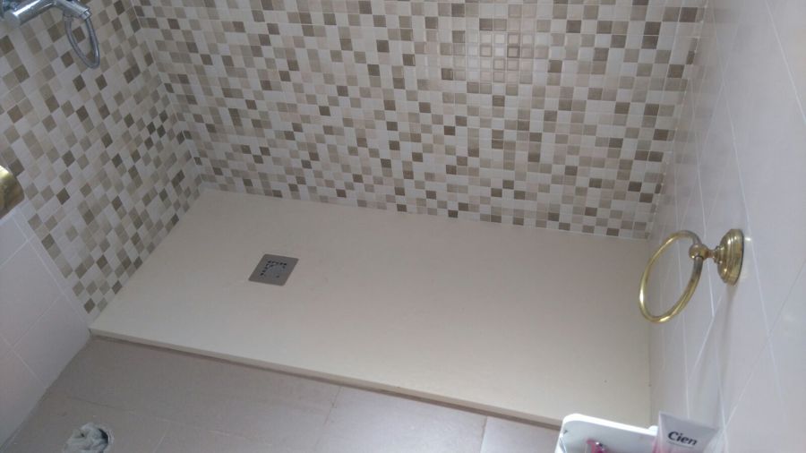 Plato de ducha beige a nivel del suelo.