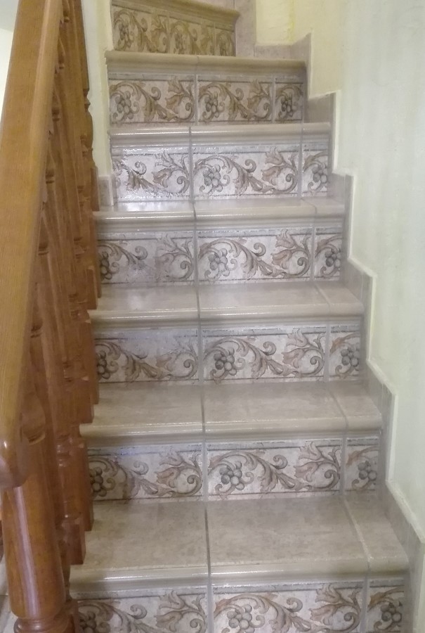 Escalera con peldaños y tabica con cenefa decorativa