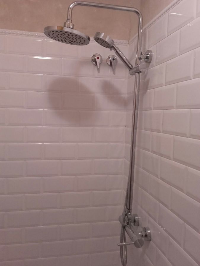 Ducha sobre los azulejos blancos