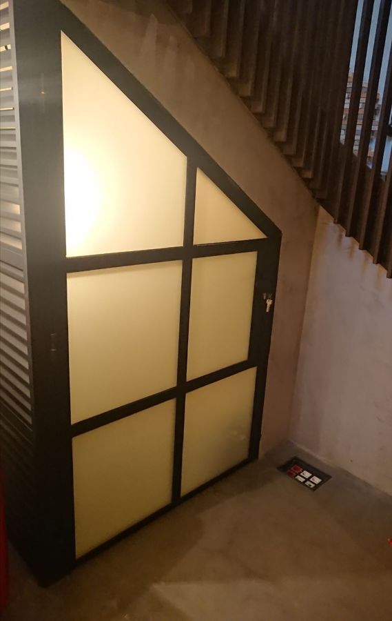 Puerta de hierro lacada al horno en color negro bajo escalera con cristales al ácido