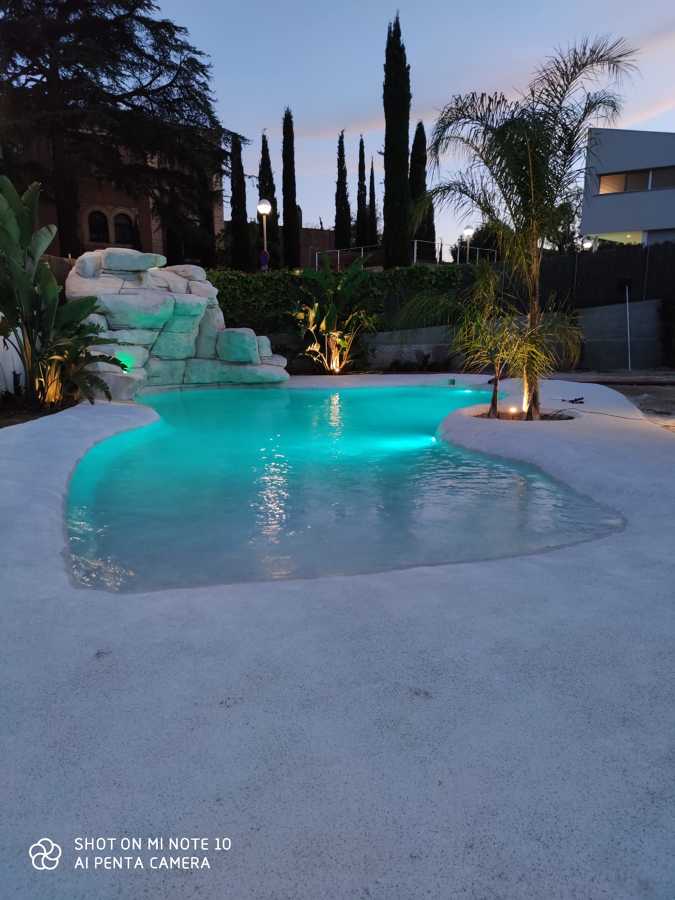 Piscina estilo playa, por la noche