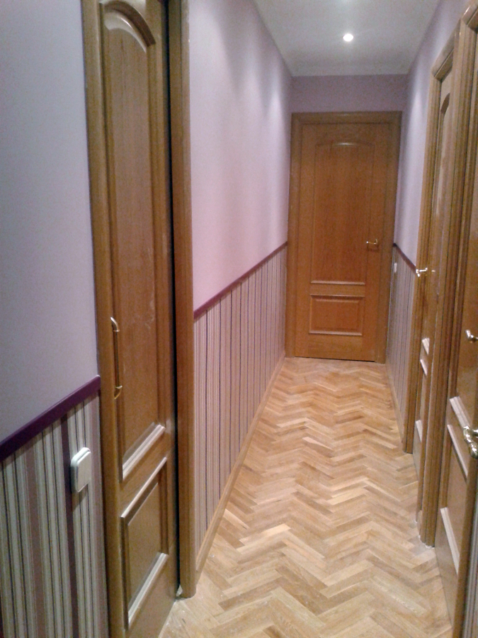 Instalación de zócalo de papel pintado en pasillo.