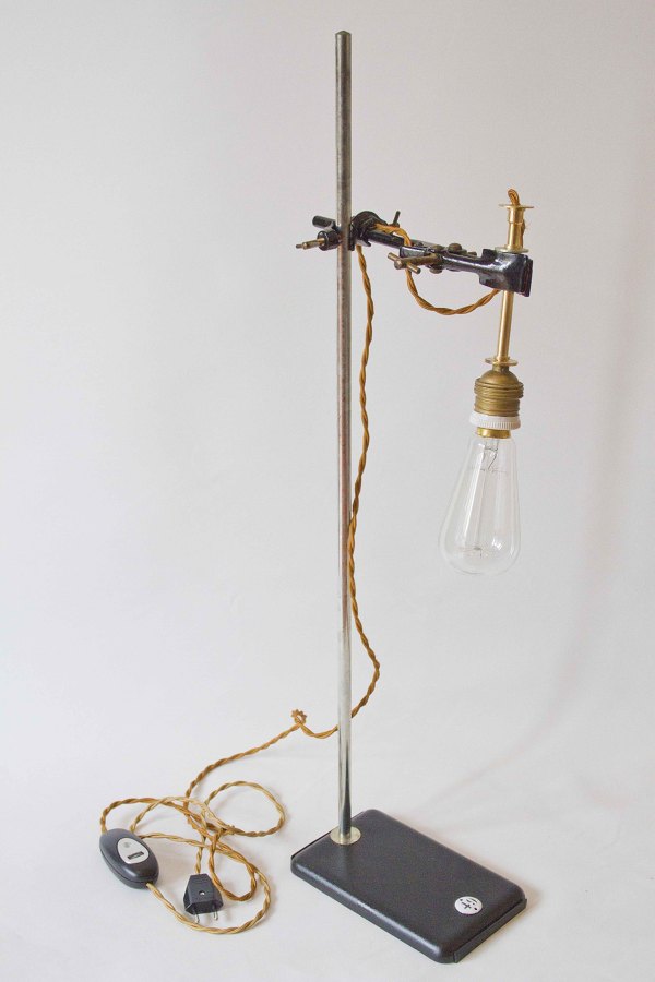 Original lámpara vintage realizada con tripode de los años `50. El casquillo es cerámico e incluye una bombilla incandescente. Cuenta con un regulador para el encendido y apagado. Lleva enchufe.