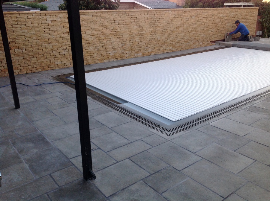 Muro rústico y persiana en piscina 