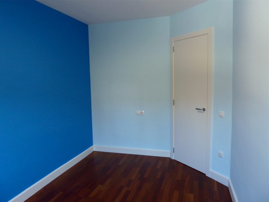 Habitació infantil pintada amb dos tons de blau i la porta i sòcols lacats amb Sikken satura blanc.