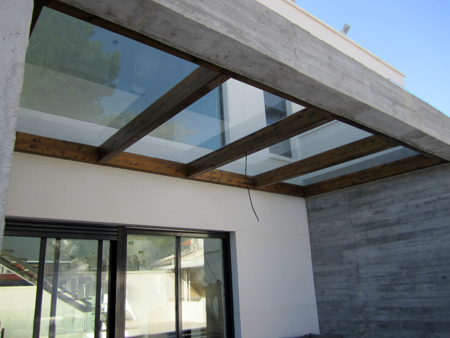 Pergola madera y cierre cristal sobre muros hormigon visto