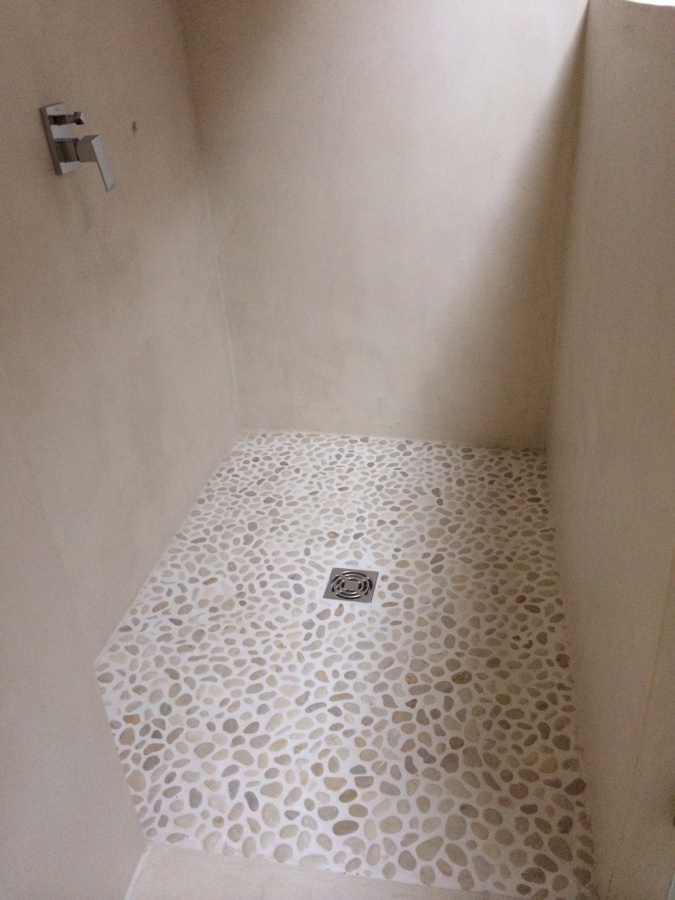 Plato de ducha de piedras de río y paramentos de microcemento