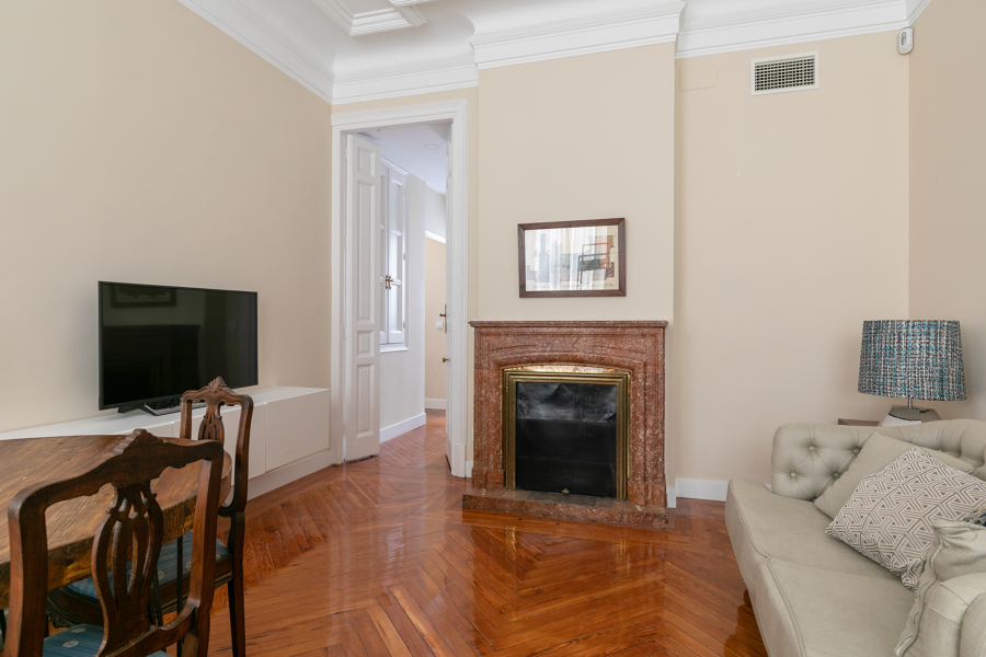Habitación con parqué de madera natural y chimenea de mármol
