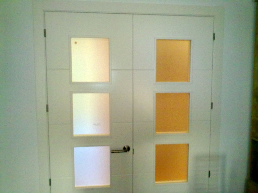 Puerta lacada en blanco de dos hojas con entrecalles horizontales, vidrio mateado y manilla en L