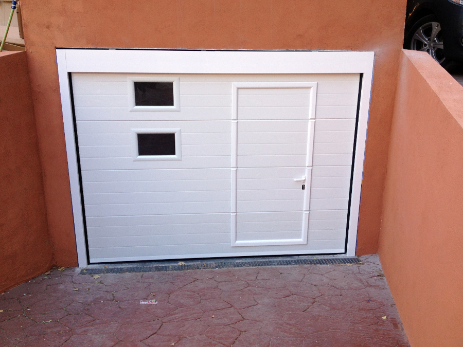 Puerta seccional blanca con peatonal incorporada y ventanas