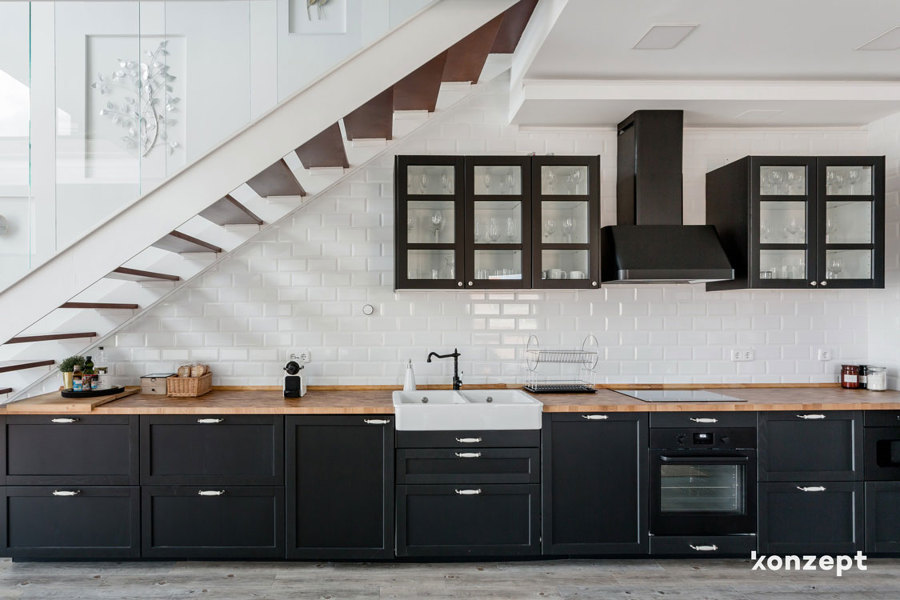 Cocina con muebles negros y encimera de madera