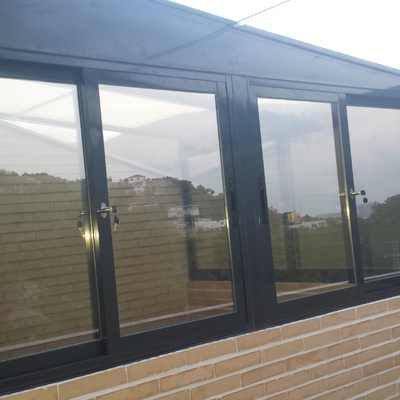 Cerramiento total terraza ladrillo visto ventanas y techo aluminio y cristal.