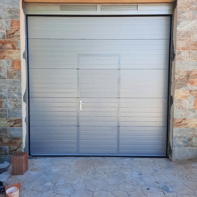 Puerta seccional con Puerta peatonal en gris plata