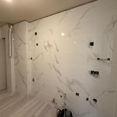 Alicatado de baño con porcelánico de gran formato y efecto mármol.