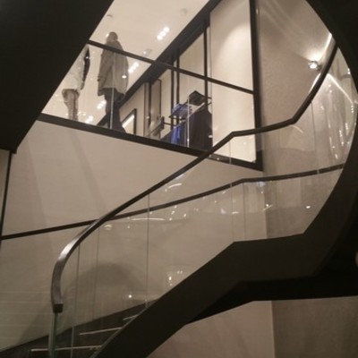 Detalle de escalera metálica helicoidal con barandilla de cristal curvo