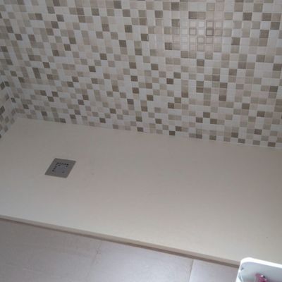 Plato de ducha beige a nivel del suelo.