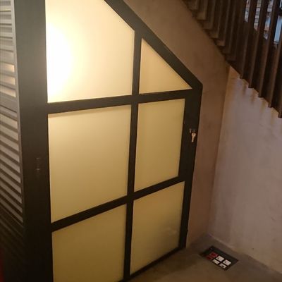 Puerta de hierro lacada al horno en color negro bajo escalera con cristales al ácido