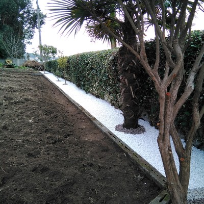 Recubrimiento de jardinera con canto rodado blanco y piedra volcánica.