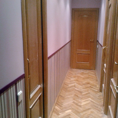 Instalación de zócalo de papel pintado en pasillo.