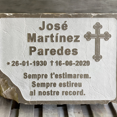 Lápida grabada en relive con dedicatoria y motivo.