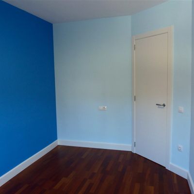 Habitació infantil pintada amb dos tons de blau i la porta i sòcols lacats amb Sikken satura blanc.