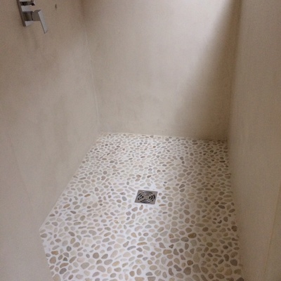 Plato de ducha de piedras de río y paramentos de microcemento