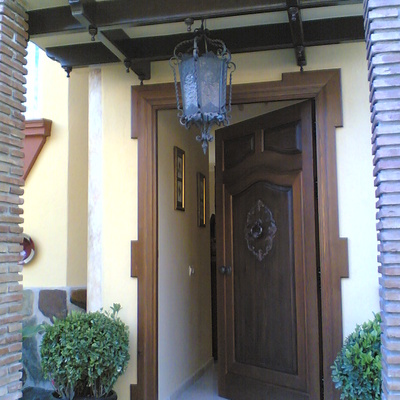 Puerta de entrada con talla y artesonado en techo.