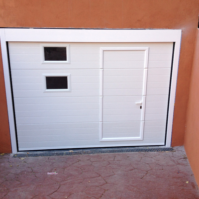 Puerta seccional blanca con peatonal incorporada y ventanas