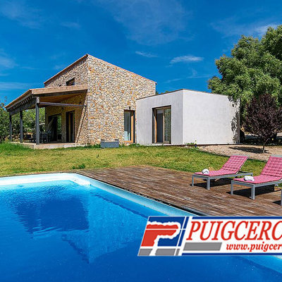 Piscina de fibra y fachada con porche de piedra viva sin junta y hormigón blanco.