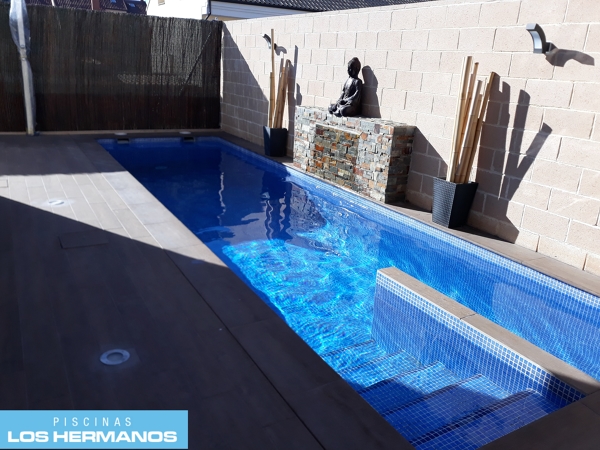 Piscina estrecha con cascada y carril de nado