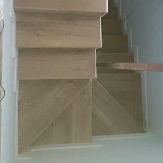 Escalera forrada de tarima quick step y rodapié blanco 