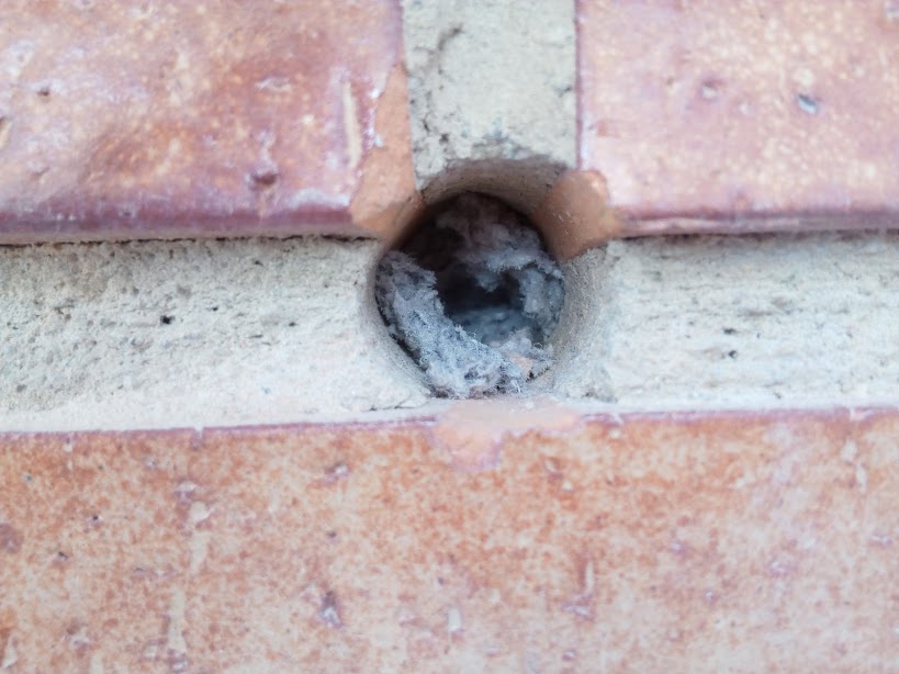 Agujero en ladrillo caravista, relleno ya de celulosa.