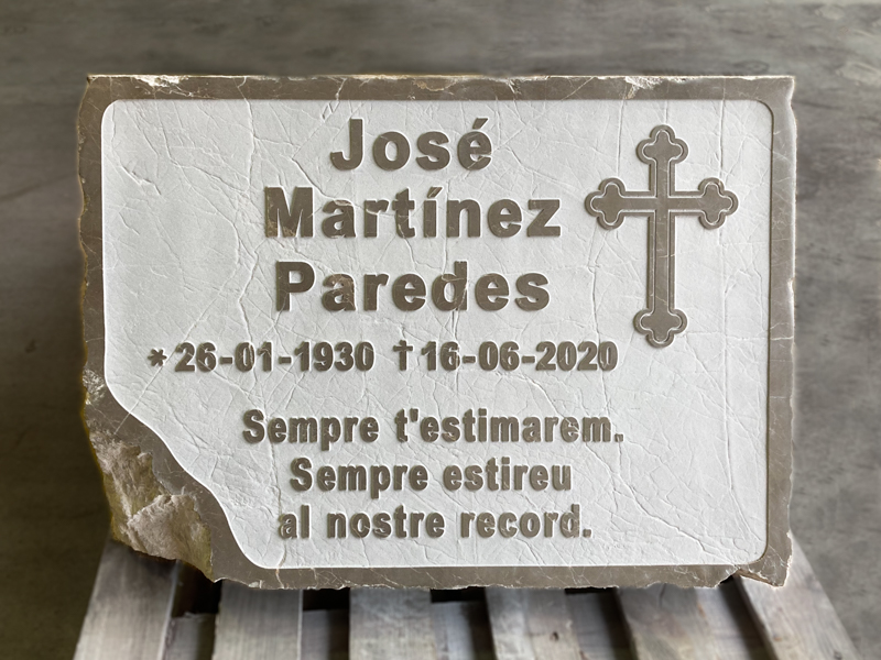Lápida grabada en relive con dedicatoria y motivo.