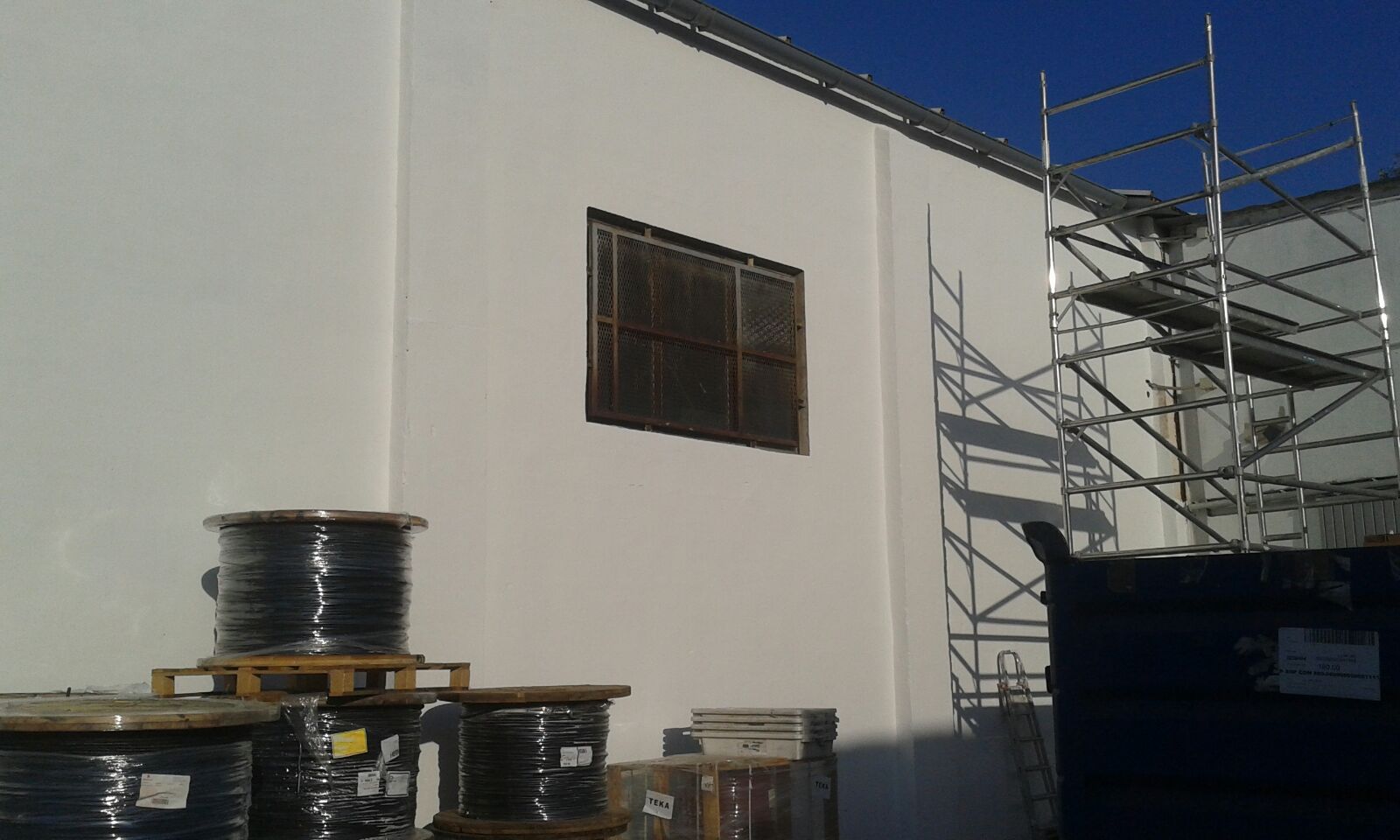 Reparación y pintado de paredes naves industriales con andamiaje.