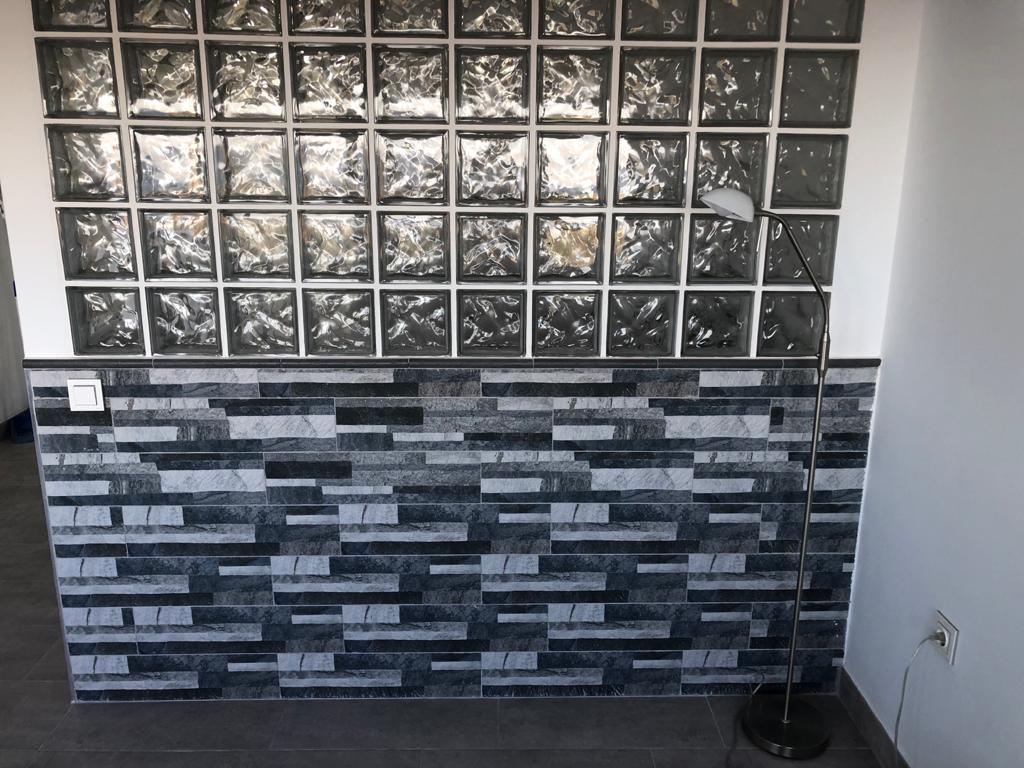 Pared con pavés, bloque de cristal y cerámica con imitación rustico/ clásico.