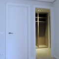 Puerta lisa lacada, embocadura de paso y armario gabanero sin puertas.