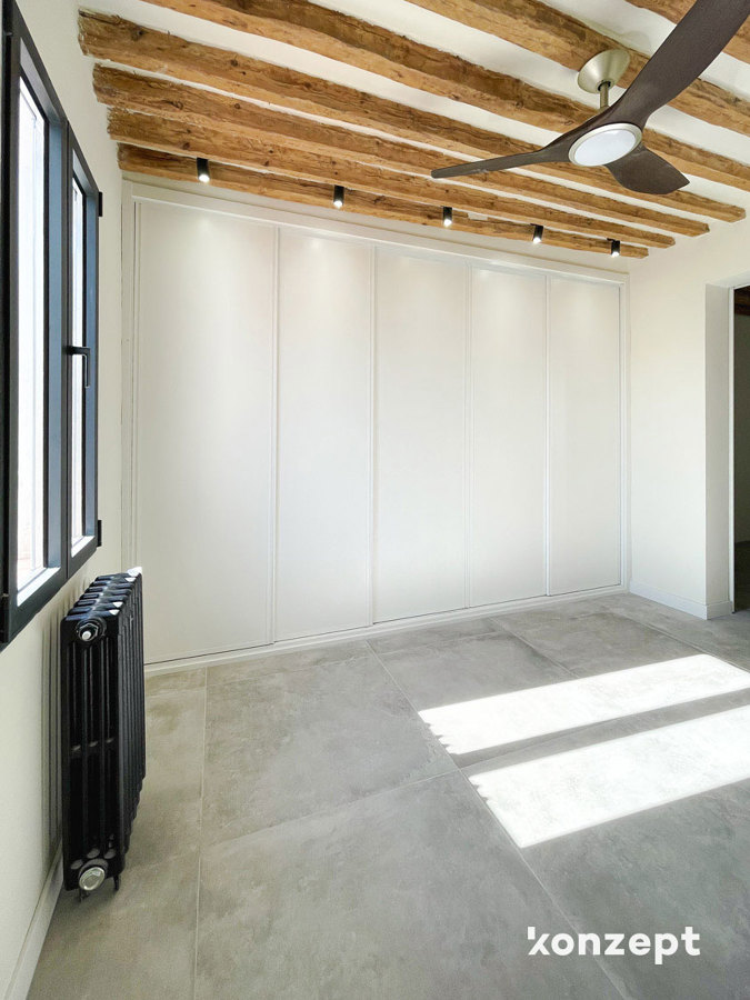 armario empotrado en dormitorio y vigas de madera vistas con detalles en negro