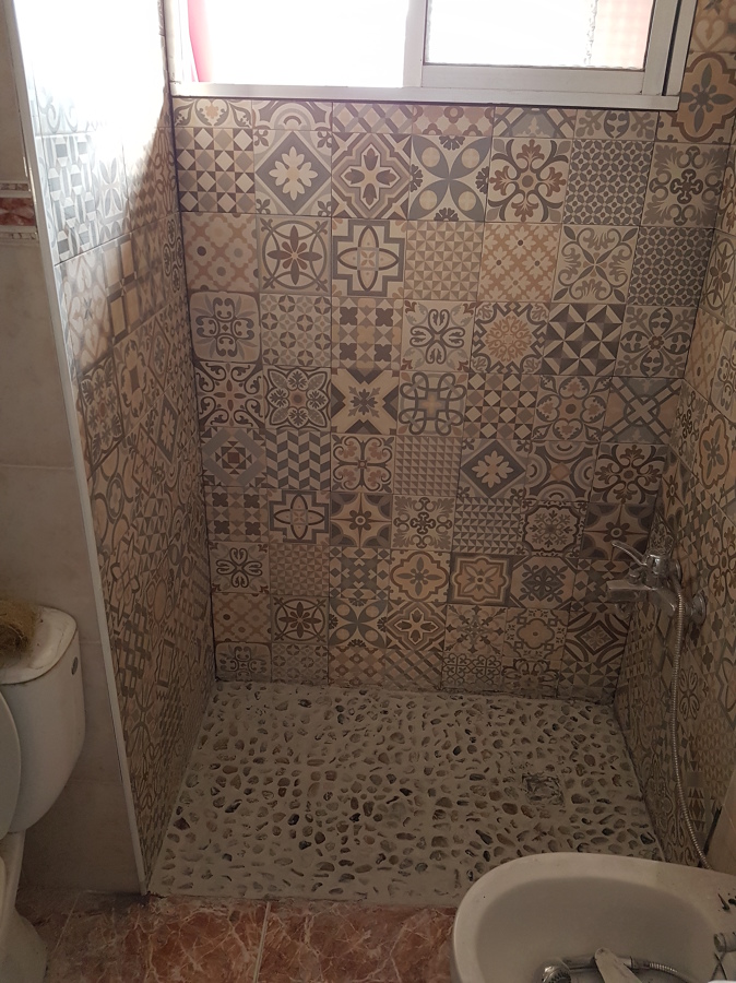 Azulejos y plato ducha de obra con piedras