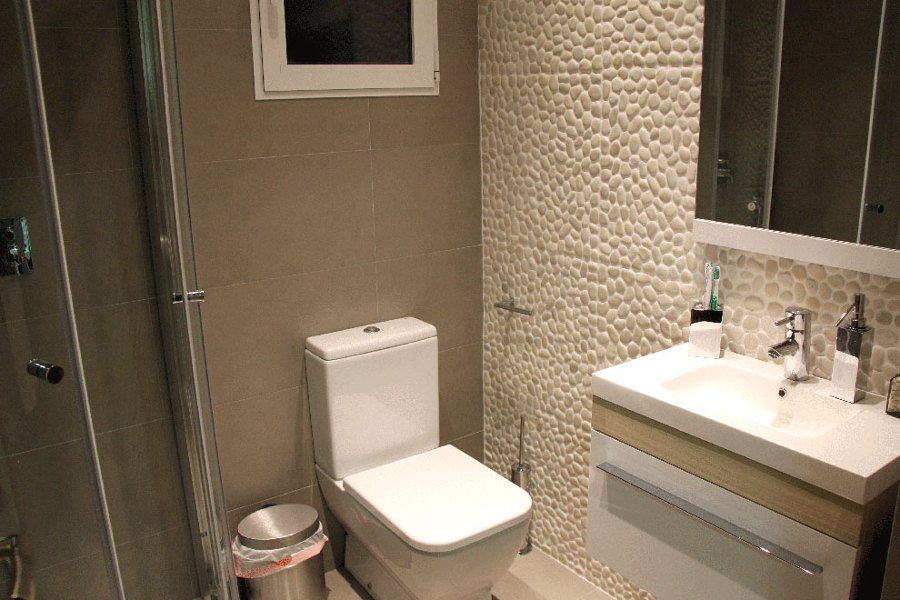 baño con pared de piedras de rió cerámica de Amado Salvador