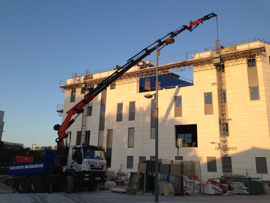 Camión pluma izando materiales en nave