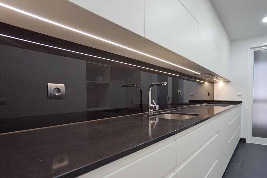 Cocina blanca con panel en vidrio negro